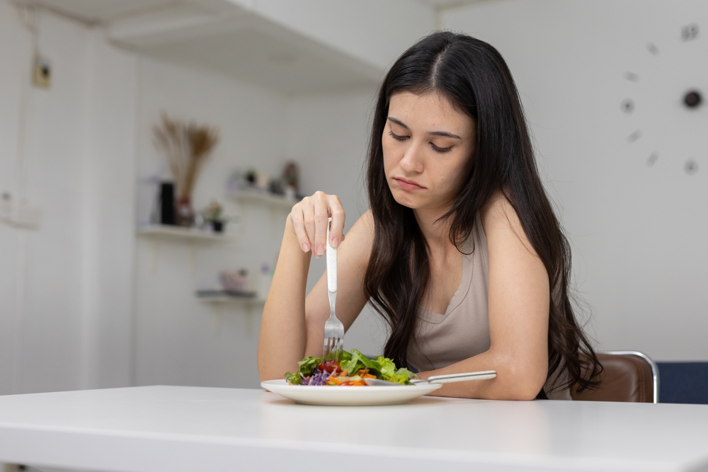 Women,Looking,Bored,Or,Unhappy,While,Eating,Salad,At,Home. eating disorder